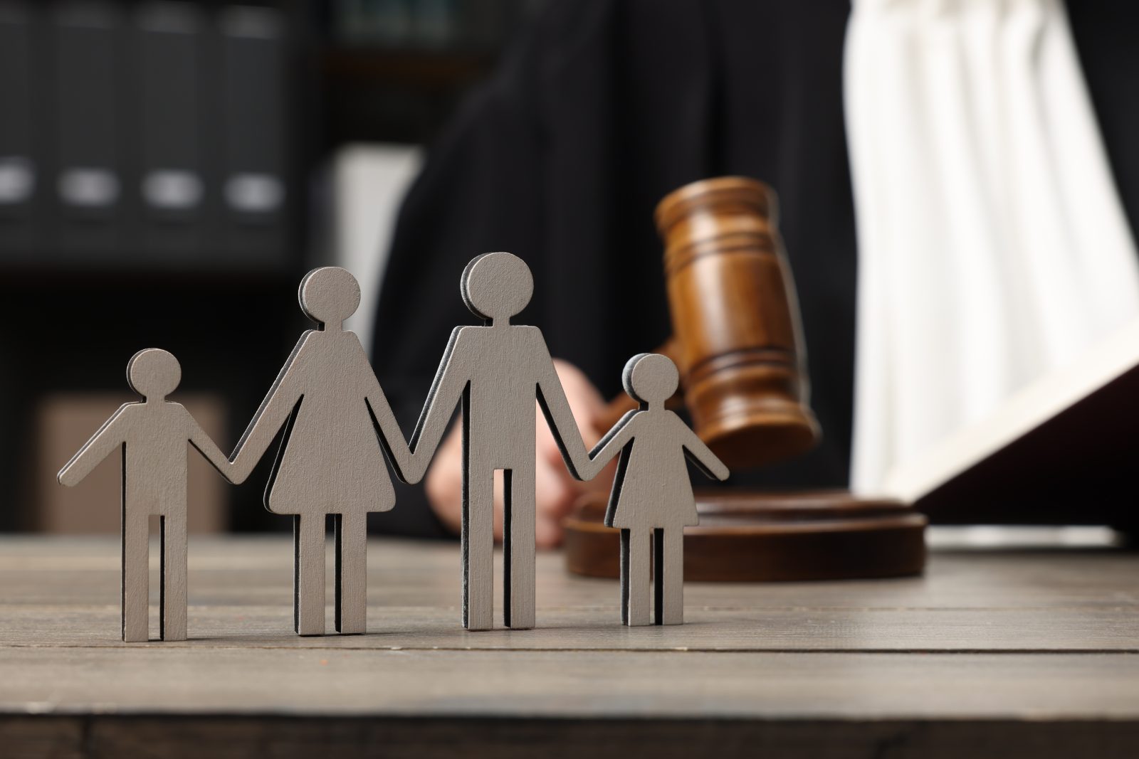 Family law. Judge with gavel sitting at wooden table, focus on figure of parents and children Lawer's Help With Divorce and Custody